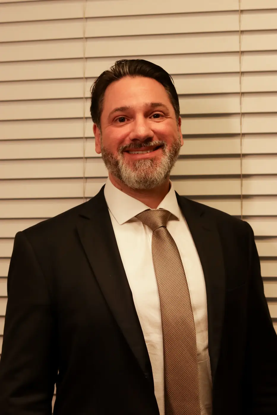 Executivo sorrindo diante de uma persiana