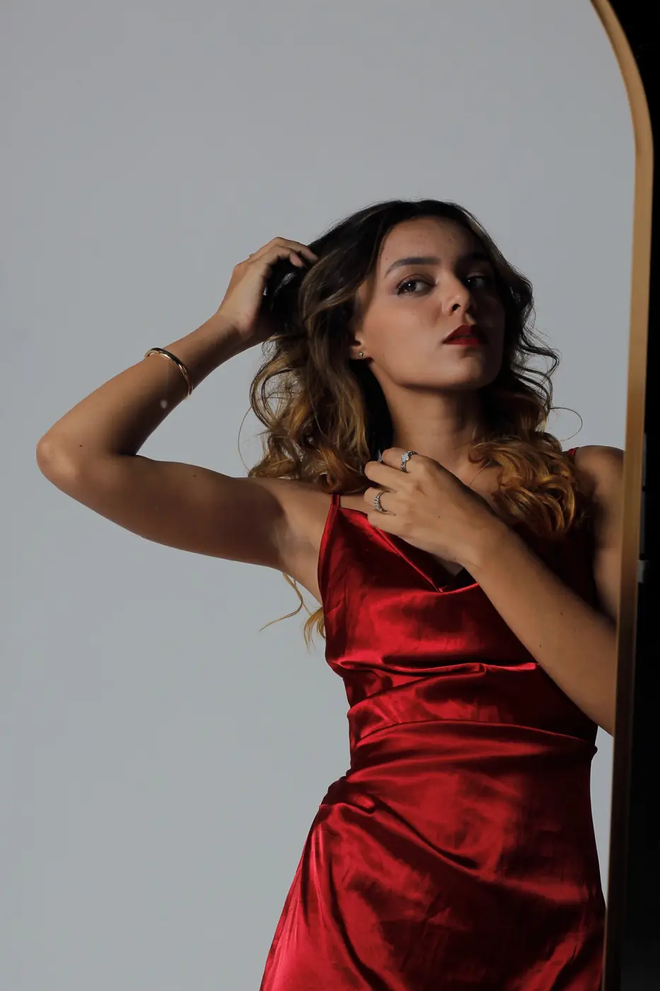 Modelo de vestido vermelho ao lado de um espelho
