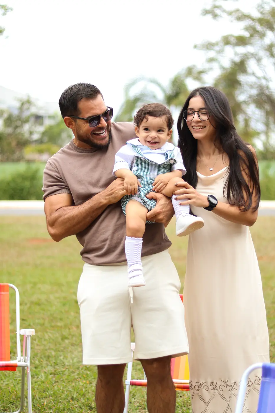 Pais segurando o filho pequeno num parque